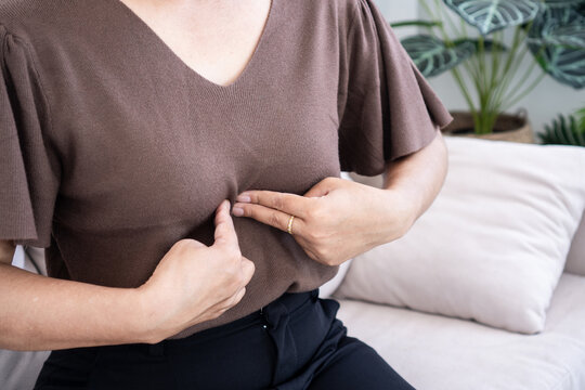 Woman touching her chest suffering from acid reflux, GERD symptoms, or heartburn. female experiencing chest pain or digestive problem at home