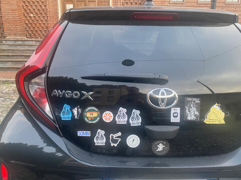 Close-up view of the rear of a black Toyota Aygo X showcasing a collection of diverse stickers applied to its tailgate