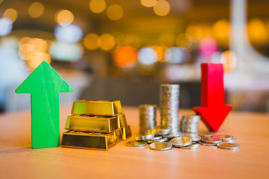 Gold investment and currency inflation concept with green upward arrow by bullion bars and red downward arrow by coin stacks on table for market volatility, commodity hedge and asset trading.