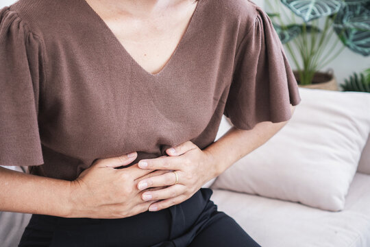 Woman holding her stomach suffering from severe stomachache, gastritis, or food poisoning. Midsection cropped shot of adult female experiencing abdominal pain