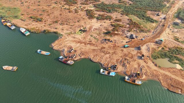 Sand carrying boats lined up at river sand mining site India natural resource extraction industry