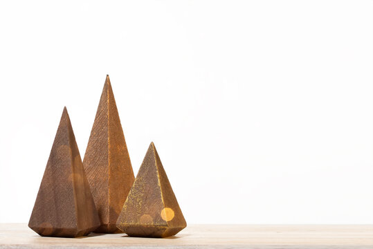 Minimalist wooden Christmas tree trio with a golden glitter bokeh on a wooden surface. Perfect for holiday sales, winter home decor themes, and festive seasonal promotions.
