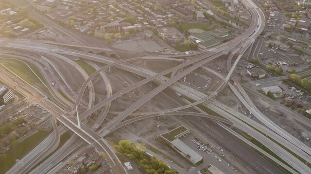 Curving ramps of the Turcot Interchange cross active rail lines and work zones under soft morning sun from a high drone flyover.