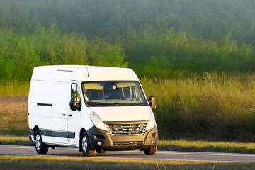 White cargo van driving on rural road © AlexGo