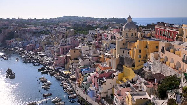 Colorful Marina di Corricella houses and church dome rise above a small boat-filled harbor on Procida island.