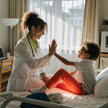 Smiling female doctor give high five to little biracial patient
