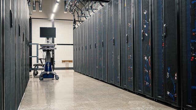 Modern data center interior with rows of server racks and a mobile diagnostic monitor datacenter corridor technology