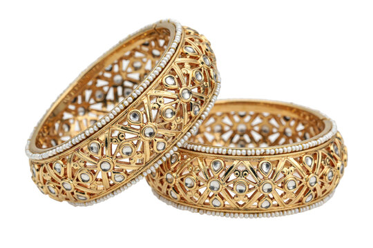 Pair of ornate gold bangles featuring intricate filigree patterns and small white stone accents isolated on a transparent background