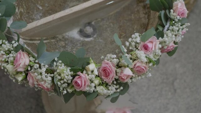 Pink rose and baby breath flower crown resting on stone wall before wedding ceremony