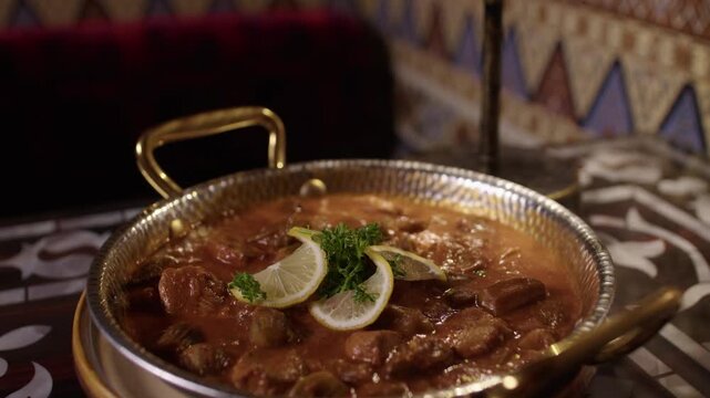 Traditional Turkish stew served in a metal pan on a patterned restaurant table