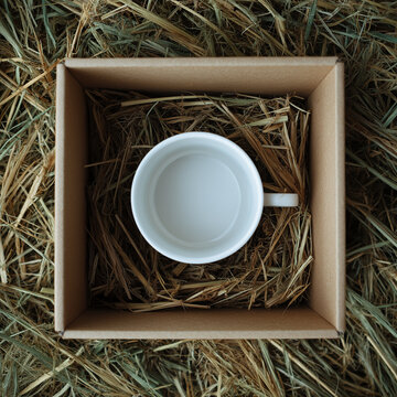 Top view white mug in a box on the hay