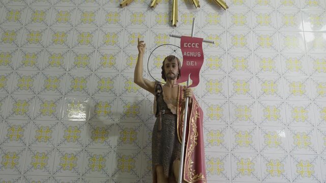 Saint John the Baptist statue with Ecce Agnus Dei banner on azulejo wall in Portugal