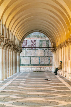 Solitary figure sits in historic Venetian arcade