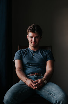 Handsome smiling young man sits in a chair for a portrait