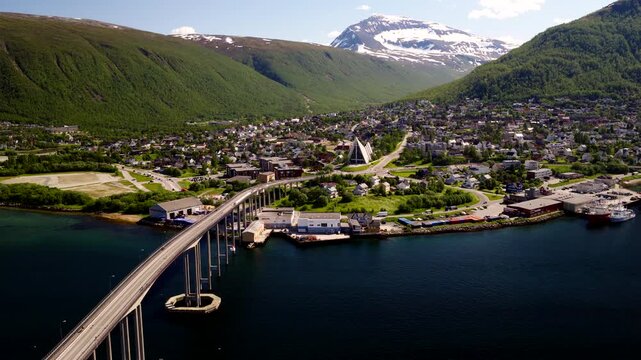 Tromso Norway showing the Arctic Cathedral Tromso Bridge waterfront neighbourhoods and surrounding mountains beside the Tromsoysundet strait in summer, aerial view