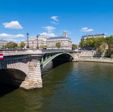 Pont Notre Dame bridge crossing the Seine River with city buildings under a blue sky