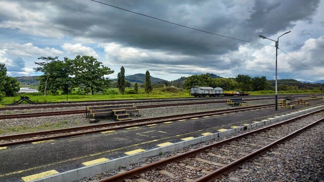 Empty railway station platform with tracks freight wagons cloudy sky