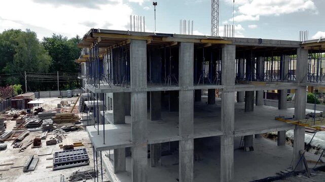 Unfinished multistory concrete building rises above a residential district, Active building site represents engineering teamwork and residential development