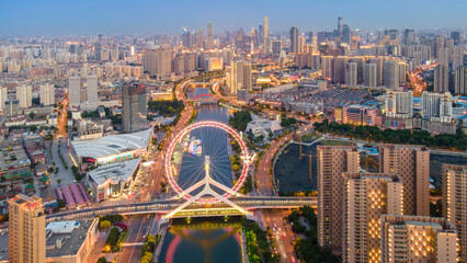 Illuminated Ferris Wheel on Urban River at Dusk © zhouyilu