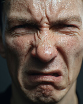 Extreme close-up of angry man showing frustration and irritation with tense facial expression under dramatic lighting