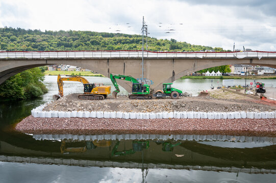 Construction site, excavators and road roller, temporary bank reinforcement, sandbags and crushed stone, bridge Wasserbillig, Luxembourg