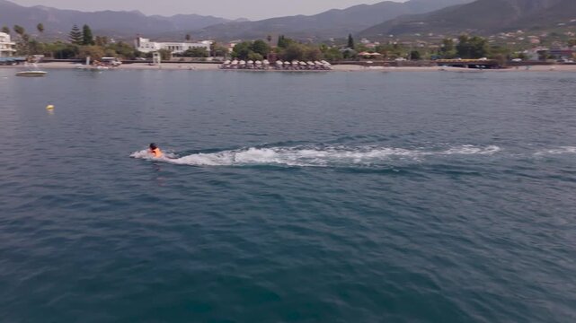 Woman Gliding Along the Sea Surface with Flyboard Equipment and Raising a Hand to the Camera, Kalamata, Greece
