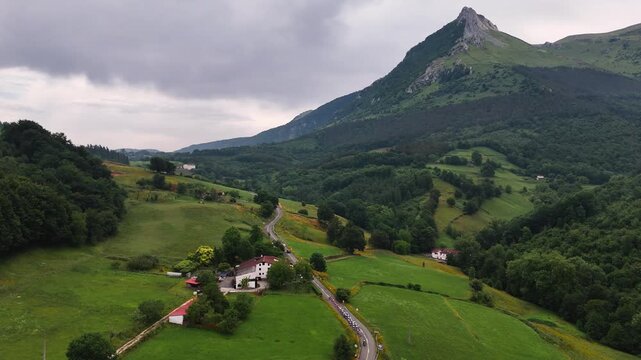 Drone view of a cycling race climbing in the basque mountains below the Txindoki mountain, at the Basque Country.