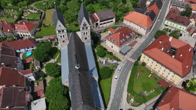 Summer drone footage showing medieval Friesach, old fortified walls, rooftops, towers, hills, serene atmosphere, warm daylight, gentle cinematic motion