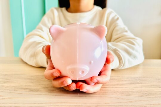 豚の貯金箱に貯金する子供の手元