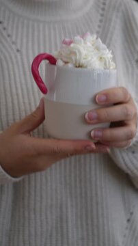 Woman drinking marshmallow hot chocolate with candy cane