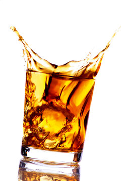 Ice cube falling into whiskey glass