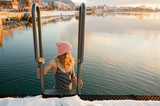 Woman swimming in cold lake during winter for healthy lifestyle