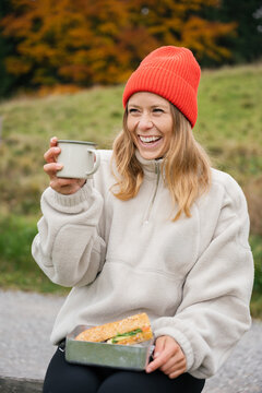Happy woman takes a break with a snack on a forest trail