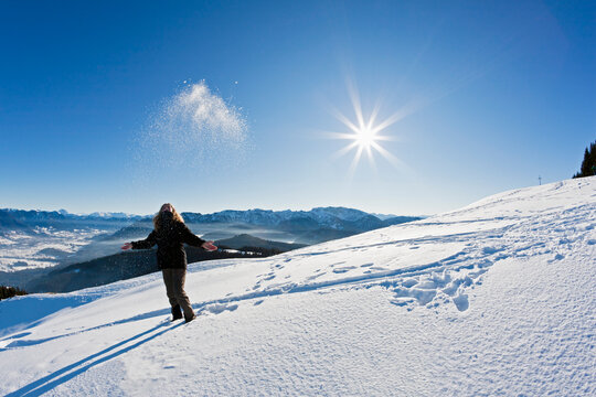 Germany, Bavaria, Blomberg, Woman hiker at Zwiesel mountain throwing snow