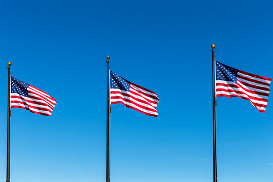 Three American flags against blue sky