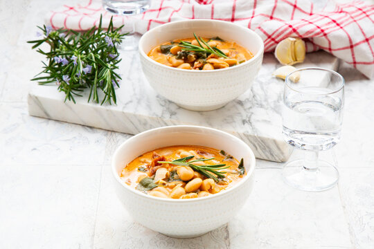 Creamy white bean stew with rosemary sits on a marble table