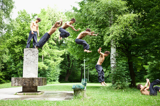 Germany, Bavaria, Young man jumping from fountain