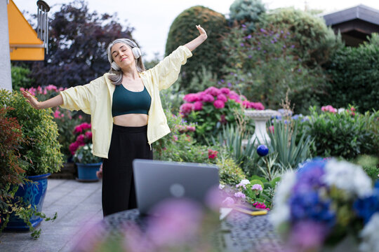 A relaxed woman stretches her body in the garden during a break