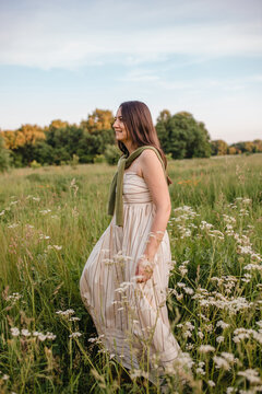 Smiling mature woman walks through a peaceful meadow wearing a dress