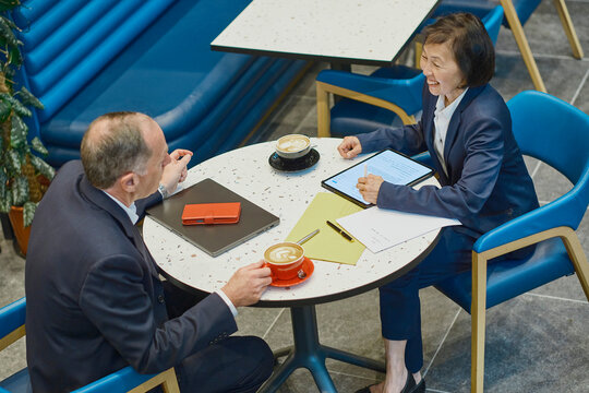 A man and woman discuss a report in a coffee shop