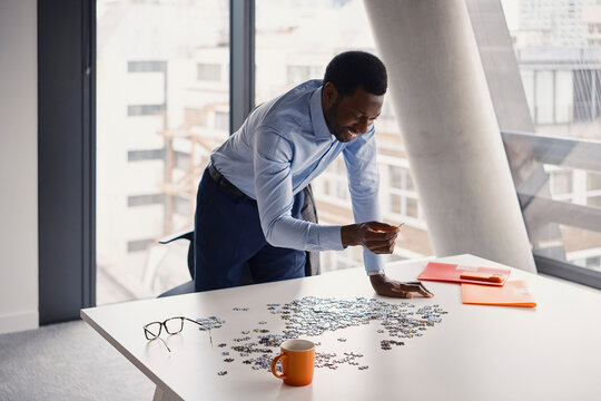 Businessman solves a jigsaw puzzle on a table in a London office