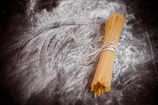 Spaghetti on wooden table with flour