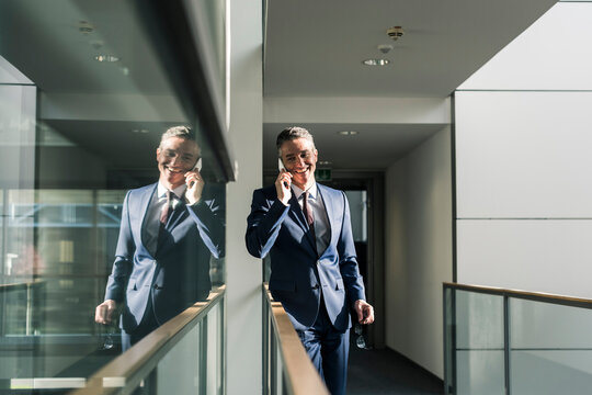 Smiling businessman talking on cell phone on office floor