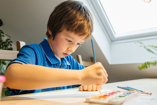 Young boy concentrating on painting watercolor art