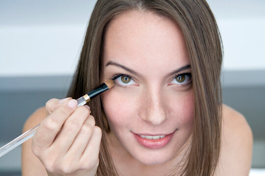 Young woman applying eye shadow, portrait,, close-up