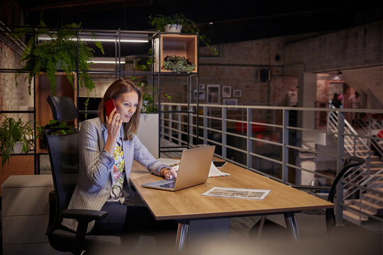 Businesswoman working in modern office, using laptop and phone