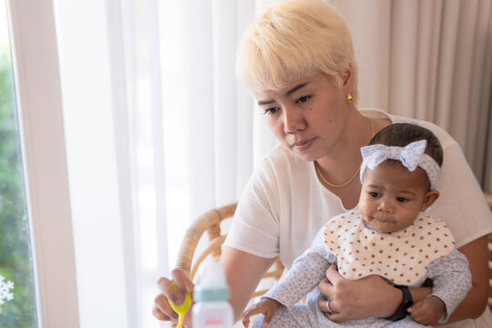 A devoted mother feeds her baby with loving attention in soft natural light, showing tender motherhood perfect for family and lifestyle themes showing genuine everyday emotion.