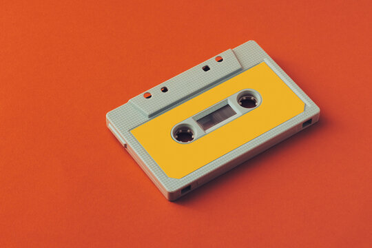 A vintage Yellow cassette tape centered on a vivid orange background,