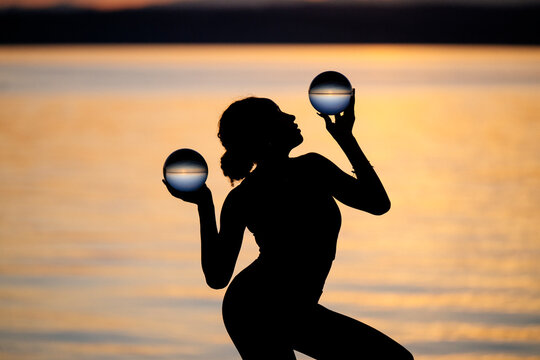 Silhouette of Hispanic woman balancing crystal balls