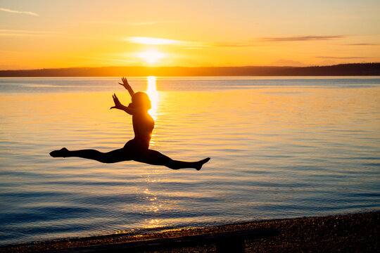 Silhouette of Hispanic woman performing split leap yoga pose